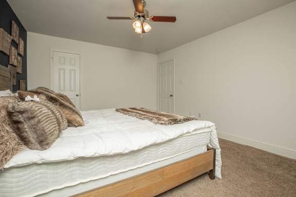 A bedroom with a bed, pillows, and a ceiling fan. at The Cove at State Street Apartments, Baton Rouge, LA