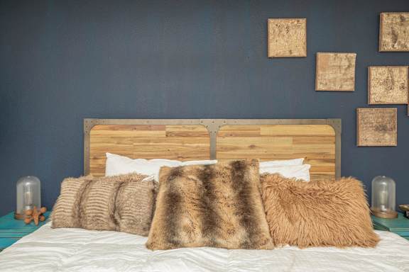 A bed with a wooden headboard and multiple pillows. at The Cove at State Street Apartments, Baton Rouge, LA, 70802