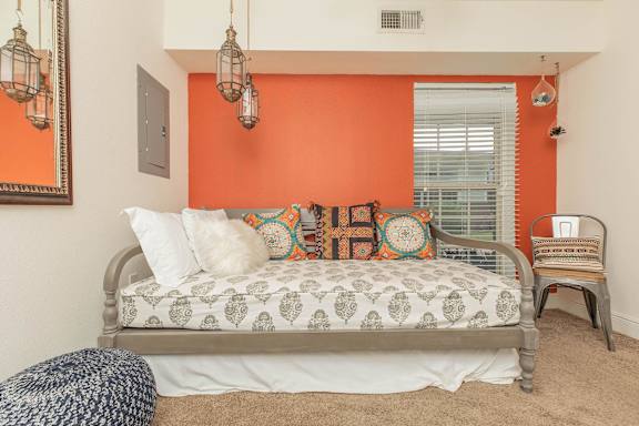 A bedroom with a bed, a chair, and a mirror. at The Cove at State Street Apartments, Baton Rouge, LA, 70802