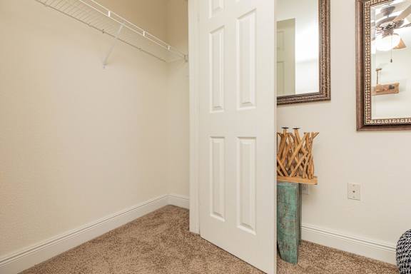 A white door is in a room with a mirror and a vase on the wall. at The Cove at State Street Apartments, Baton Rouge, LA