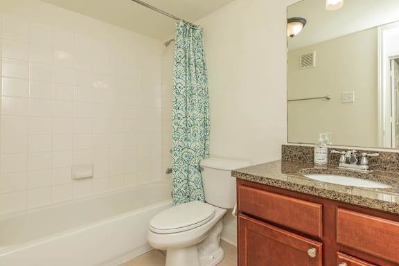 A white toilet sits next to a bathtub in a bathroom. at The Cove at State Street Apartments, Louisiana