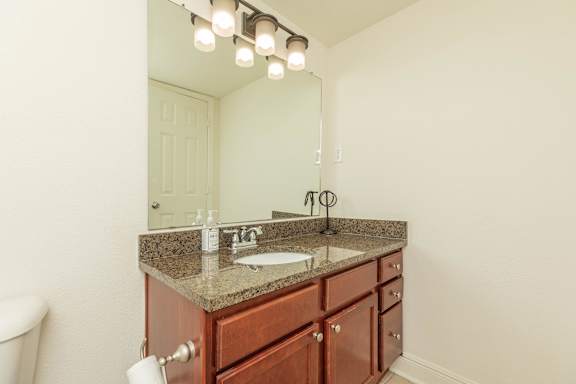 A bathroom with a sink, mirror, and lights. at The Cove at State Street Apartments, Louisiana, 70802