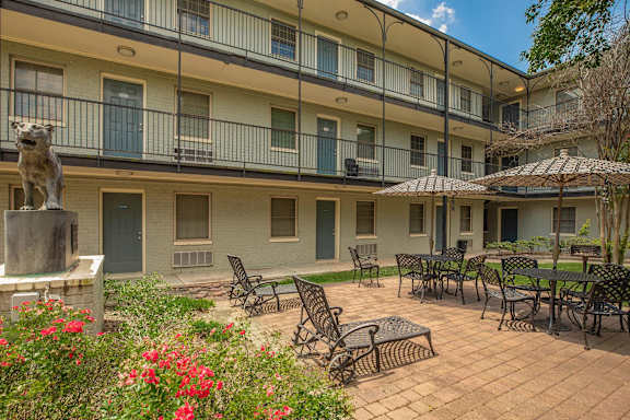 A courtyard with a statue of a lion and chairs and tables. at The Cove at State Street Apartments, Baton Rouge, LA