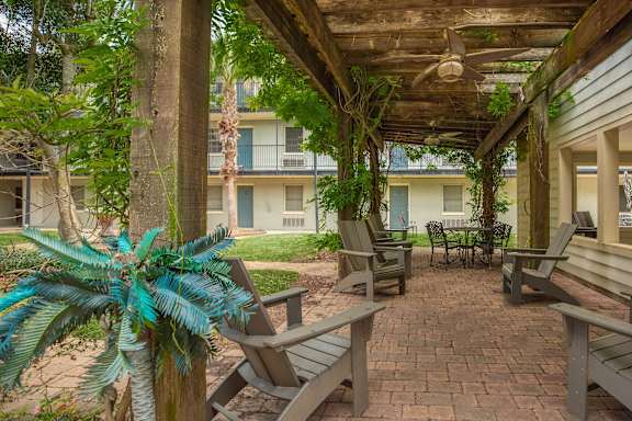 A patio with a table and chairs under a roof. at The Cove at State Street Apartments, Baton Rouge