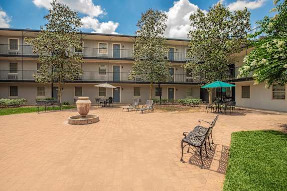 A courtyard with a fountain and chairs. at The Cove at State Street Apartments, Louisiana, 70802