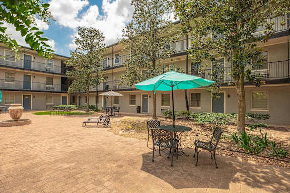 A patio with a table and chairs and a green umbrella. at The Cove at State Street Apartments, Baton Rouge, LA