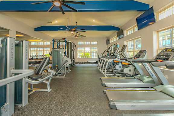 A gym with treadmills, exercise bikes, and a fan. at The Cove at State Street Apartments, Baton Rouge, LA, 70802