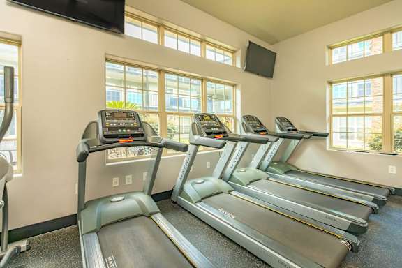 A treadmill room with a TV mounted on the wall. at The Cove at State Street Apartments, Baton Rouge, LA