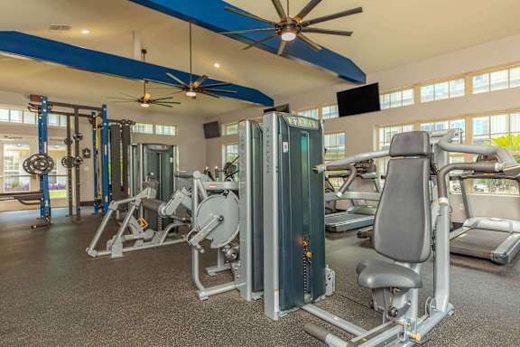 A gym with a variety of equipment including a weight machine and a bench press. at The Cove at State Street Apartments, Baton Rouge, LA