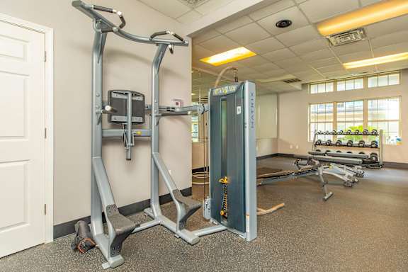 A gym with a weight machine and a row of treadmills. at The Cove at State Street Apartments, Baton Rouge, LA, 70802