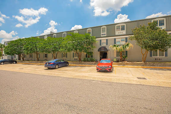 A red car is parked in a parking lot in front of a building. at The Cove at State Street Apartments, Baton Rouge, LA