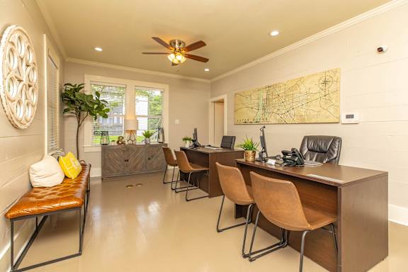 A room with a brown desk and chairs, a ceiling fan, and a map on the wall. at The Cove at State Street Apartments, Baton Rouge