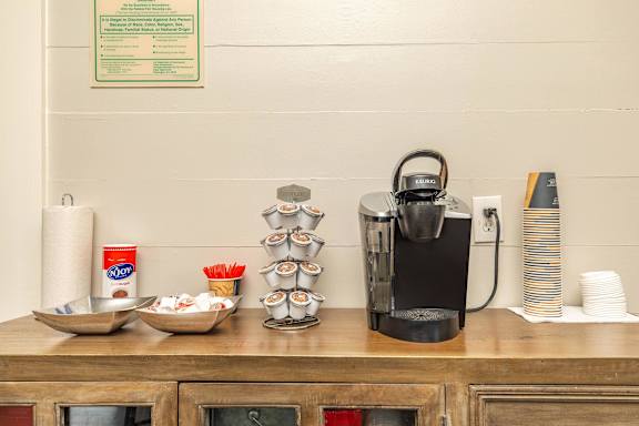 A coffee maker is on a wooden counter with a sign above it. at The Cove at State Street Apartments, Baton Rouge, Louisiana