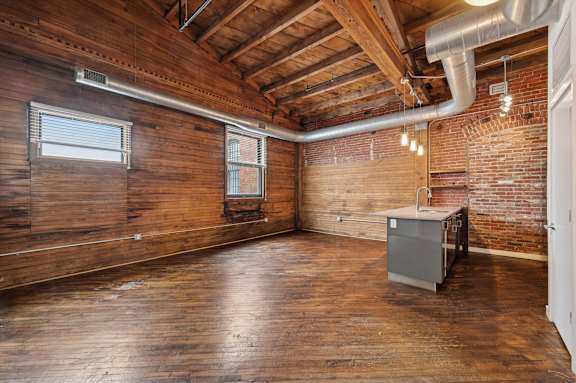 A room with wooden walls and a brick wall with a window and a radiator.