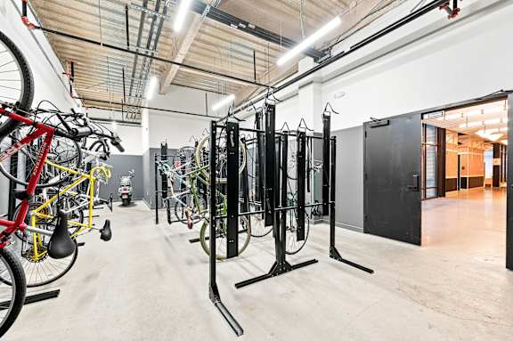 A gym with a row of black weight machines and bicycles.