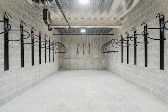 A long hallway with a white floor and walls, and black metal racks on the wall.