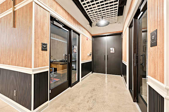 A hallway with black doors and wooden walls.