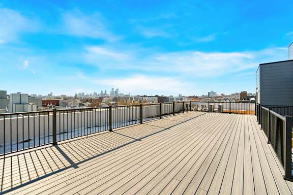A wooden deck with a metal railing overlooking a city skyline.