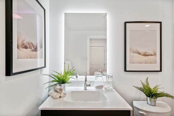 A bathroom with a white sink and two framed pictures on the wall.