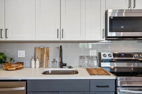 A modern kitchen with a stainless steel oven and white cabinets.