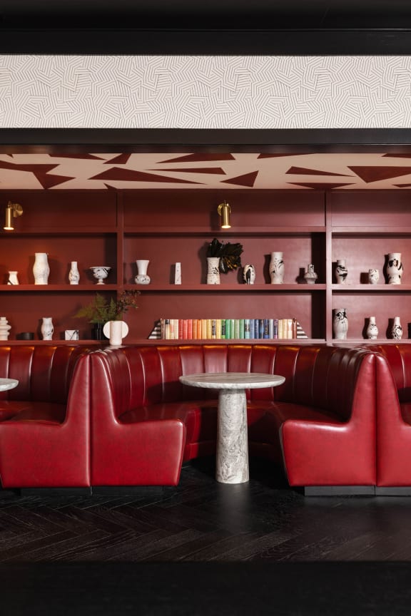 a room with red chairs and a table and bookshelves