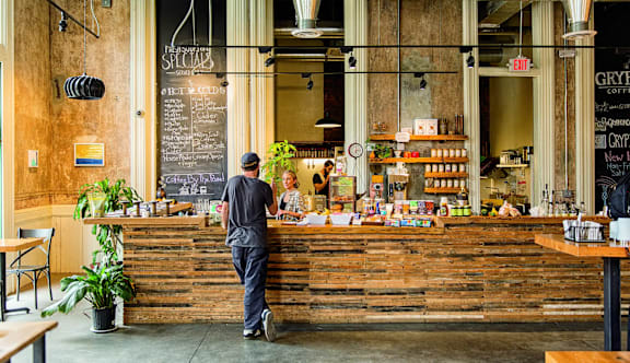 A man is standing at the counter of a coffee shop.