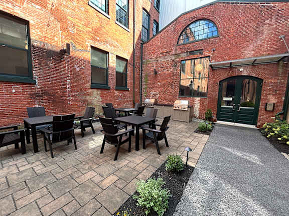 A patio with a table and chairs is surrounded by a brick building.