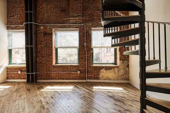 A room with a spiral staircase and wooden floors.