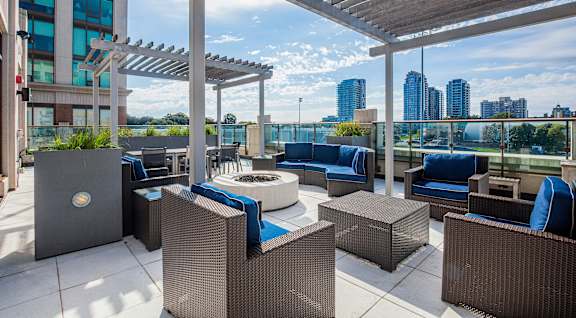 A patio with a fire pit and seating area overlooking a city skyline.