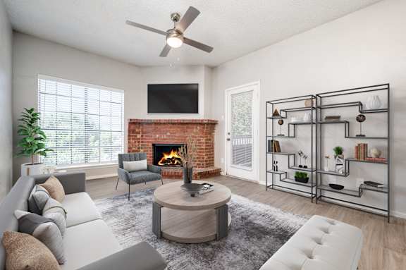 an open living room with a fireplace and a ceiling fan