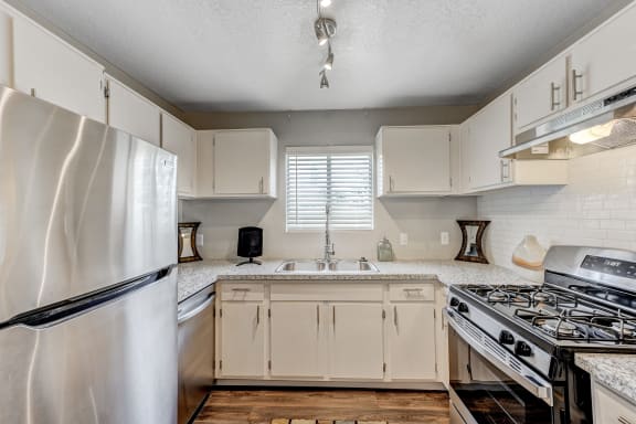 an updated kitchen with white cabinets and stainless steel appliances