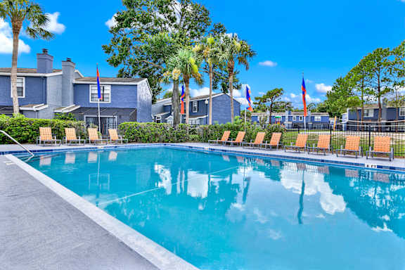 A swimming pool in front of a house with palm trees.