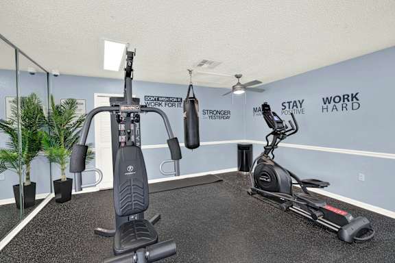 A gym room with a treadmill, a stationary bike, a rowing machine, and a wall with the words "Stay Positive" and "Work Hard".