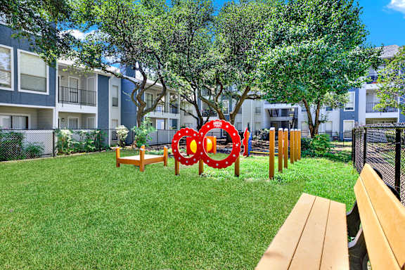 A playground with a red and white circular structure in the middle of a grassy area.