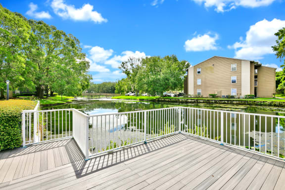 A deck with a white railing overlooks a pond and trees  at Village Springs in Orlando FL.