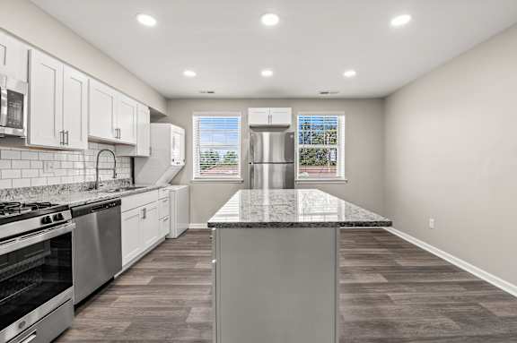 a kitchen with white cabinets and a large island with granite countertops