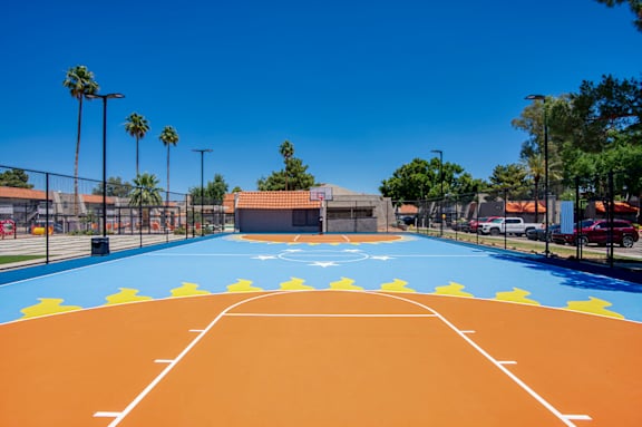 A basketball court with a blue and orange surface and white lines.