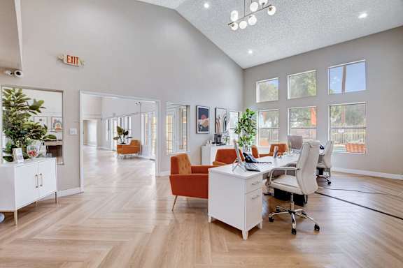 A room with a white desk and orange chairs.