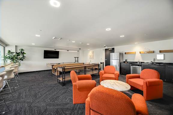A modern living room with orange chairs and a wooden table.