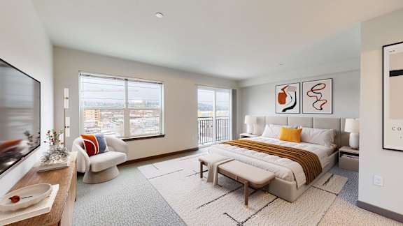 A well-lit bedroom with a large bed and a window overlooking the city.