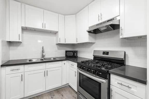 A kitchen with white cabinets and black countertops.at Palms at Menlo, Los Angeles, CA