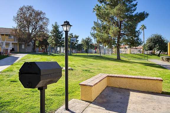 A black mailbox and a lamp post stand on a grassy area next to a brick structure.