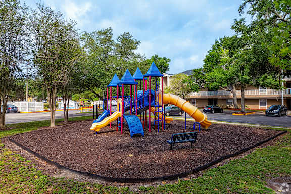 a playground with a blue and yellow slide in a park