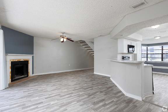 an empty living room with a fireplace and a ceiling fan