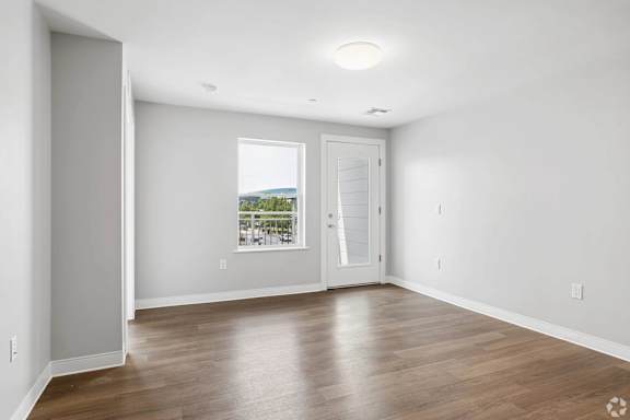 A spacious room with wooden floors and a large window.
