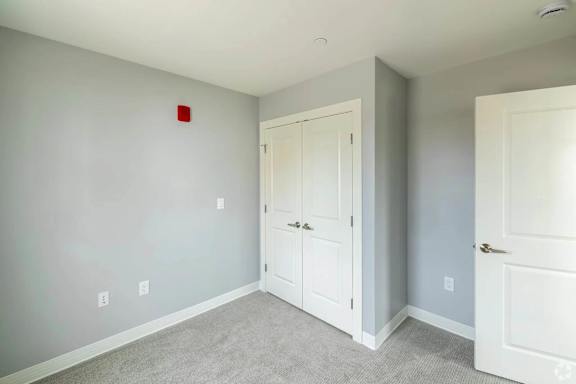 A room with a white door and a red square on the wall.