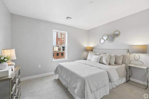 A bedroom with a large bed and a window overlooking a cityscape.