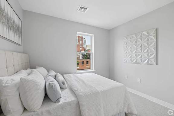 A bedroom with a large bed and a window overlooking a city.