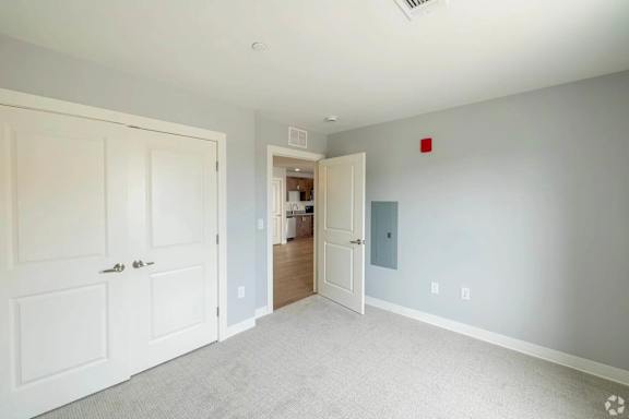 A room with a white door and a carpeted floor.