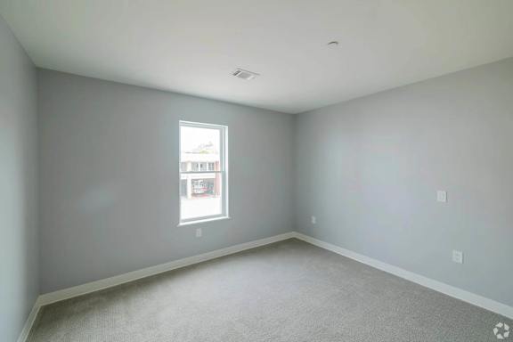 A room with a window and a carpeted floor.